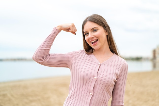 Young pretty blonde woman doing strong gesture