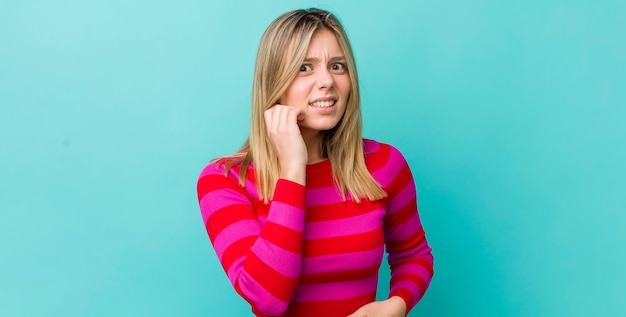 Foto giovane bella donna bionda che si sente stressata, frustrata e stanca, sfregando il collo doloroso con uno sguardo preoccupato e turbato