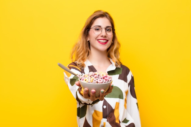 Young pretty blonde woman having a breakfast bowl of cereals