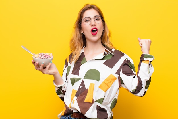 Young pretty blonde woman having a breakfast bowl of cereals