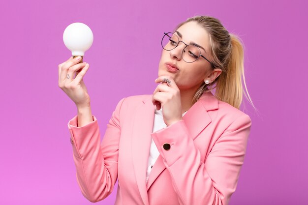 Giovane donna bionda graziosa che ha un'idea con una lampadina