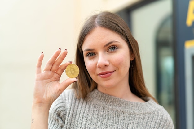 Young pretty blonde woman holding a Bitcoin