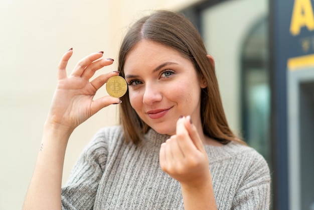 Young pretty blonde woman holding a Bitcoin