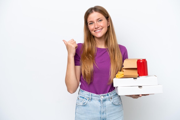 Young pretty blonde woman holding fast food isolated on white background pointing to the side to present a product