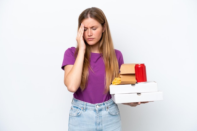 Young pretty blonde woman holding fast food isolated on white background with headache