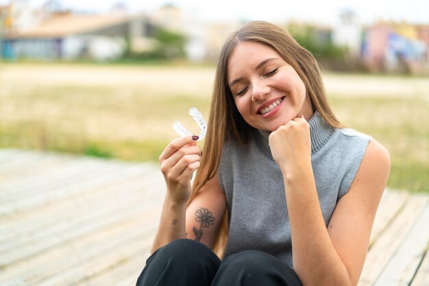 幸せな表情で目に見えないブレースを保持している若いきれいなブロンドの女性