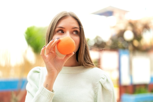 オレンジを保持している若いきれいなブロンドの女性