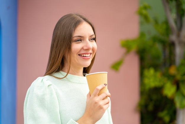 Young pretty blonde woman holding a take away coffee with happy expression