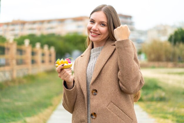 勝利を祝って屋外でタルトを保持している若いきれいなブロンドの女性