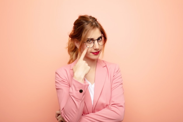 Photo young pretty blonde woman keeping an eye on you, not trusting, watching and staying alert and vigilant. business concept