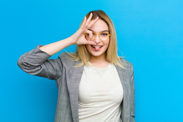 Giovane donna bionda graziosa che sorride felicemente con la faccia divertente