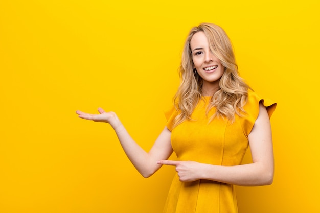 Young pretty blonde woman smiling and pointing