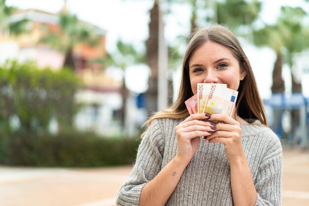 たくさんのお金を取る若いかなり金髪の女性