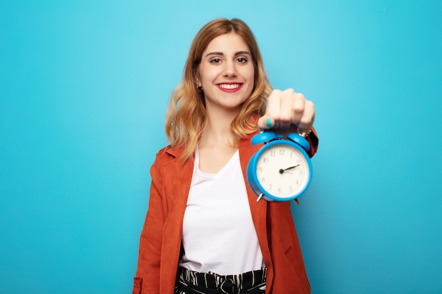 Young pretty blonde woman with an alarm clock