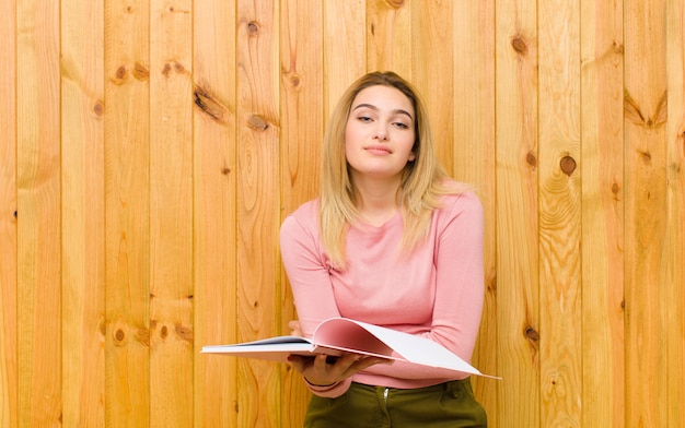 Young pretty blonde woman with books  wood wall