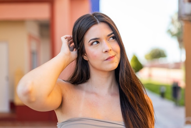 Young pretty Brazilian woman at outdoors having doubts