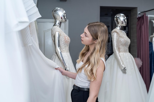 Foto giovane bella sposa guardando i migliori vestiti in negozio