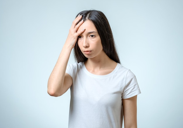 Young pretty brunette girl touching her head on white background