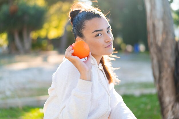 Photo young pretty brunette woman holding an orange