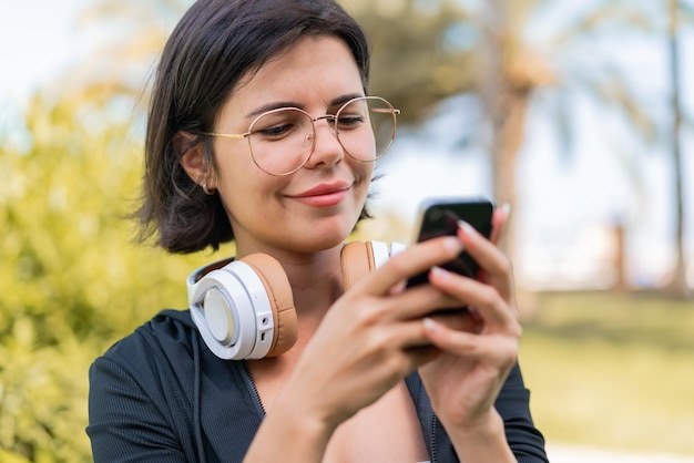 Young pretty Bulgarian woman at outdoors using mobile phone