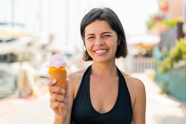 Young pretty Bulgarian woman with a cornet ice cream at outdoors smiling a lot