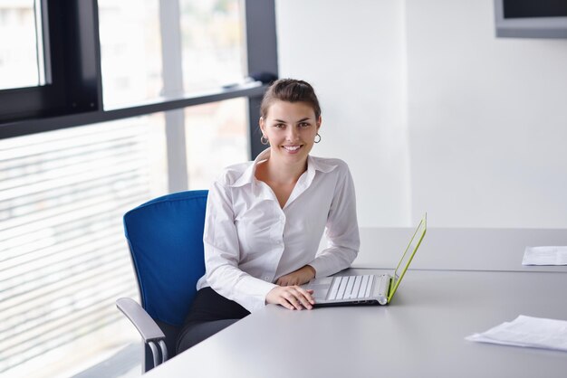 Молодая красивая деловая женщина с ноутбуком в ярком современном офисе в помещении