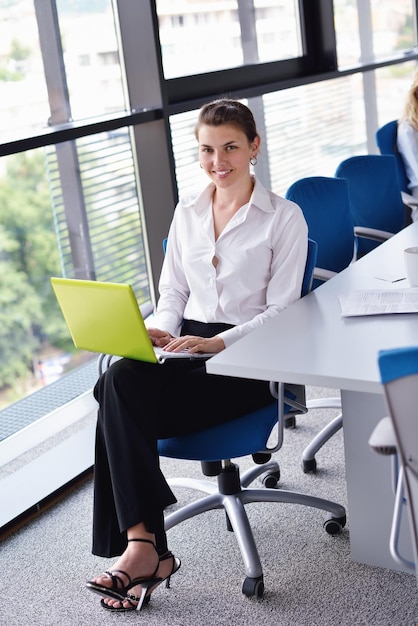 밝은 현대 사무실 실내에서 노트북을 들고 있는 젊고 예쁜 비즈니스 우먼