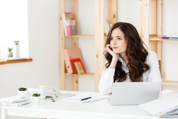 ノートブックと明るい近代的なオフィスの屋内でのドキュメントの若いかなりビジネス女性