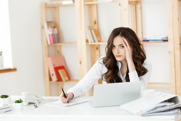 Young pretty business woman with notebook and document in the bright modern office indoors