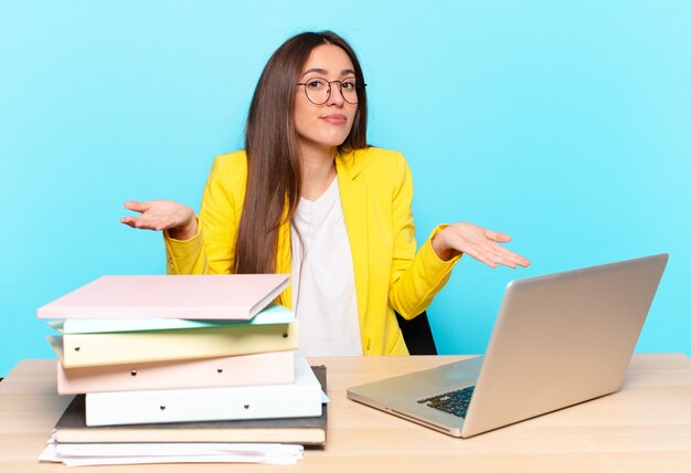 Young pretty businesswoman feeling puzzled and confused, unsure about the correct answer or decision, trying to make a choice