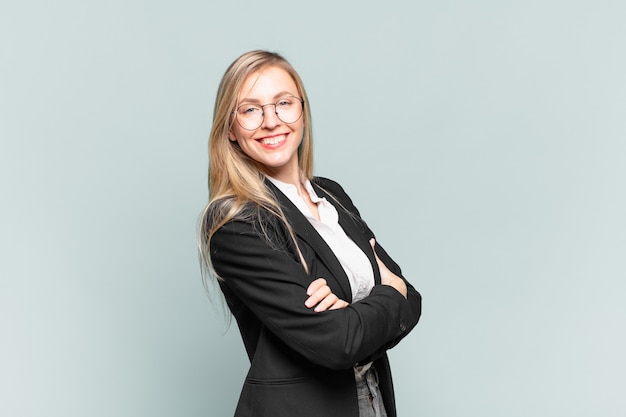 Young pretty businesswoman laughing happily with arms crossed, with a relaxed, positive and satisfied pose