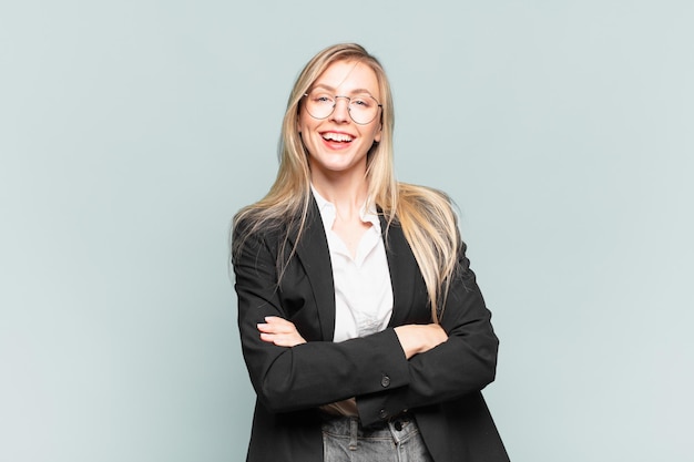 Young pretty businesswoman looking like a happy, proud and satisfied achiever smiling with arms crossed