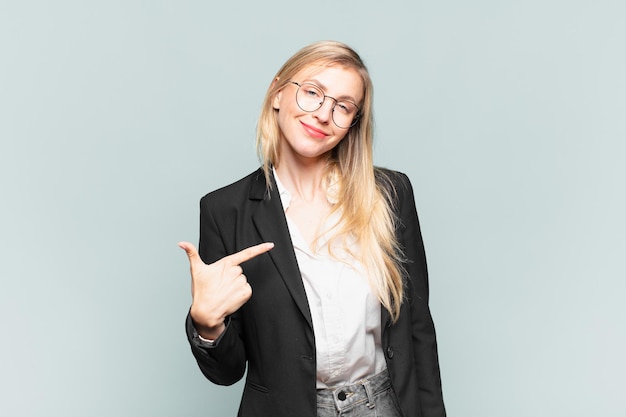 Young pretty businesswoman looking proud, confident and happy, smiling and pointing to self or making number one sign