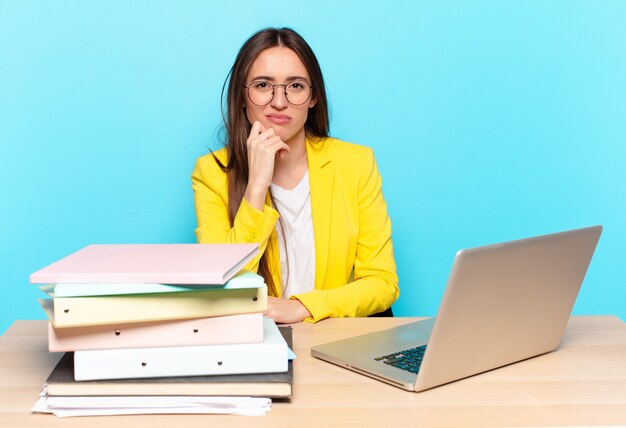 Young pretty businesswoman looking serious, confused, uncertain and thoughtful, doubting among options or choices