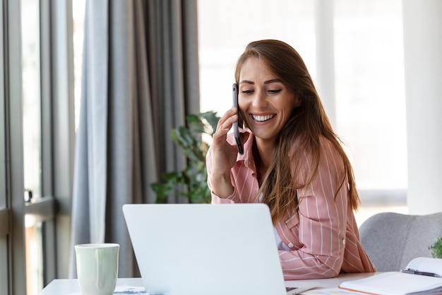 Young pretty businesswoman in the office sitting in office chair talking on her smartphone