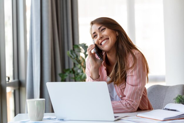 Young pretty businesswoman in the office sitting in office chair talking on her smartphone