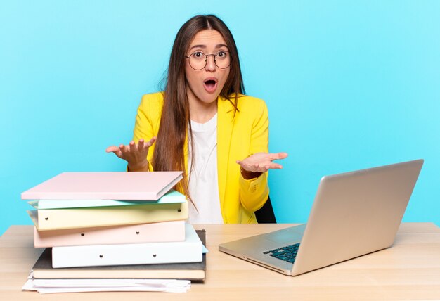 Young pretty businesswoman open-mouthed and amazed, shocked and astonished with an unbelievable surprise