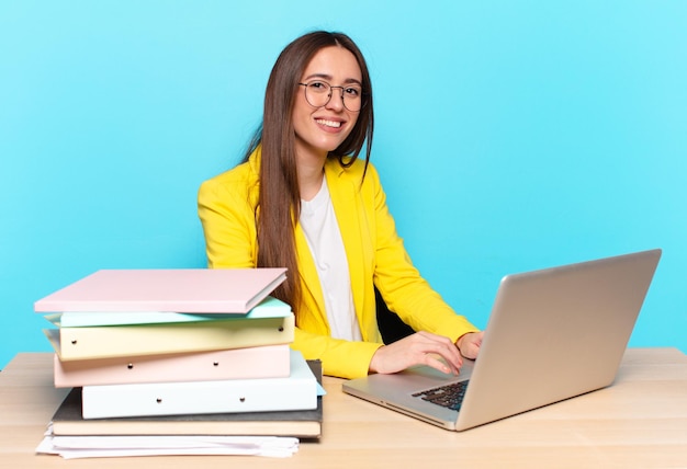 Young pretty businesswoman smiling to camera with crossed arms and a happy, confident, satisfied expression, lateral view