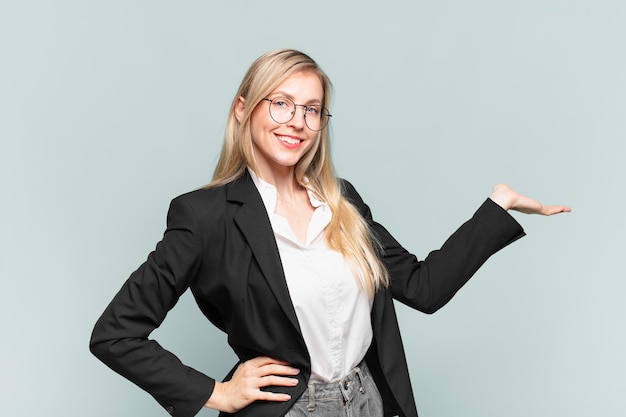 Young pretty businesswoman smiling, feeling confident, successful and happy, showing concept or idea on copy space on the side