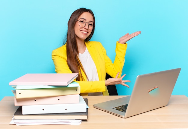 Young pretty businesswoman smiling proudly and confidently, feeling happy and satisfied and showing a concept on copy space