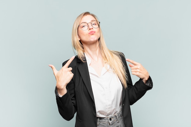 Young pretty businesswoman with a bad attitude looking proud and aggressive, pointing upwards or making fun sign with hands