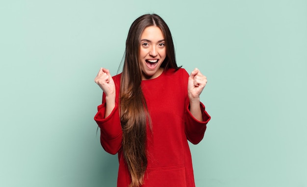 Young pretty casual woman feeling shocked, excited and happy, laughing and celebrating success, saying wow!