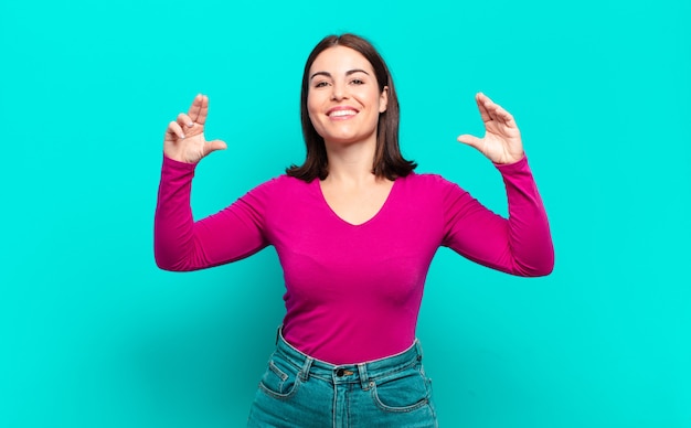 Young pretty casual woman framing or outlining own smile with both hands, looking positive and happy, wellness board
