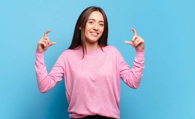 Young pretty casual woman framing or outlining own smile with both hands, looking positive and happy, wellness concept