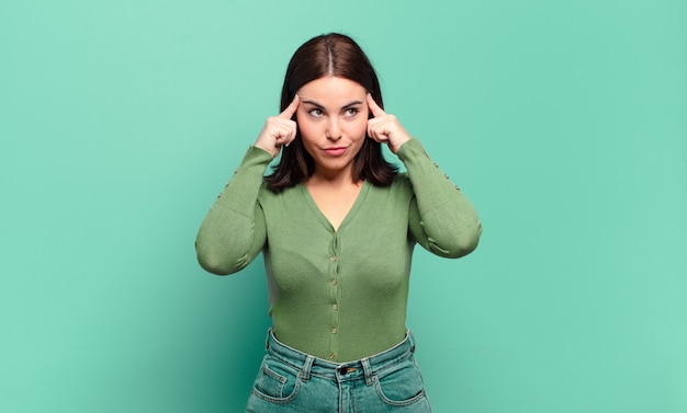 Young pretty casual woman looking concentrated and thinking hard on an idea, imagining a solution to a challenge or problem