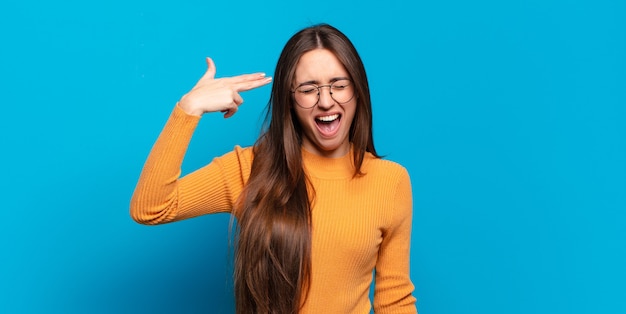 Young pretty casual woman looking unhappy and stressed, suicide gesture making gun sign with hand, pointing to head