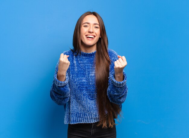 Young pretty casual woman shouting triumphantly, laughing and feeling happy and excited while celebrating success