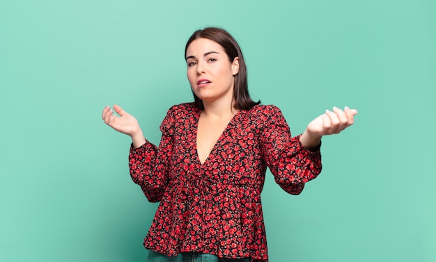 Young pretty casual woman shrugging with a dumb, crazy, confused, puzzled expression, feeling annoyed and clueless