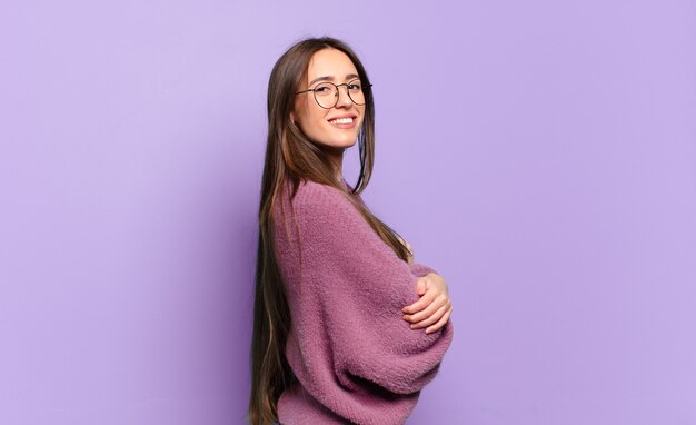 Young pretty casual woman smiling gleefully, feeling happy, satisfied and relaxed, with crossed arms and looking to the side