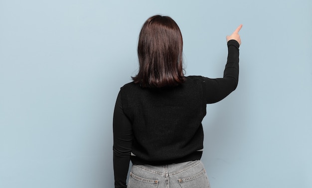 Photo young pretty casual woman standing and pointing to object